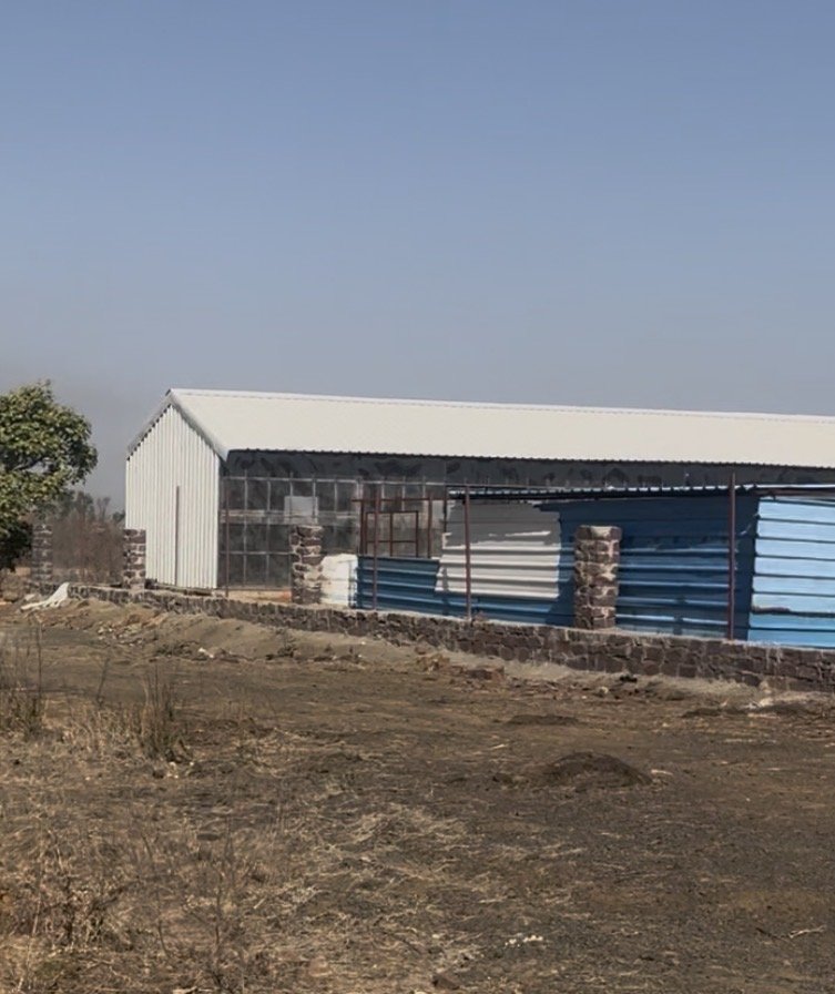 Wide view of the corrugated shelter structure on the property
